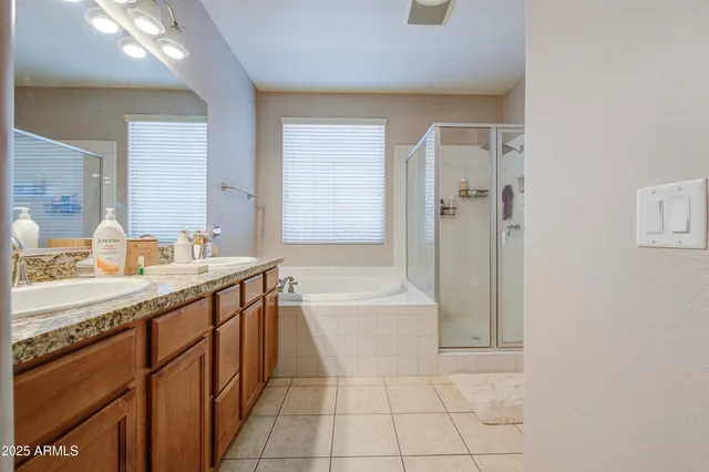 a spacious bathroom with a granite countertop sink a mirror and a bathtub