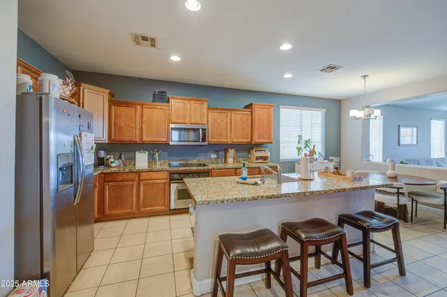 a kitchen with stainless steel appliances granite countertop a table chairs sink refrigerator and cabinets