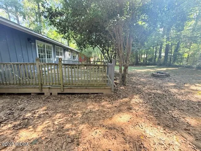 a view of backyard with wooden fence and large trees