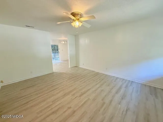 an empty room with wooden floor and ceiling fan