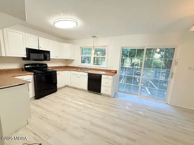 a kitchen with stainless steel appliances granite countertop a stove top oven a sink dishwasher a refrigerator and a microwave oven with wooden floor
