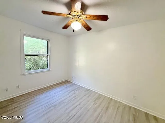 an empty room with a window and a fan