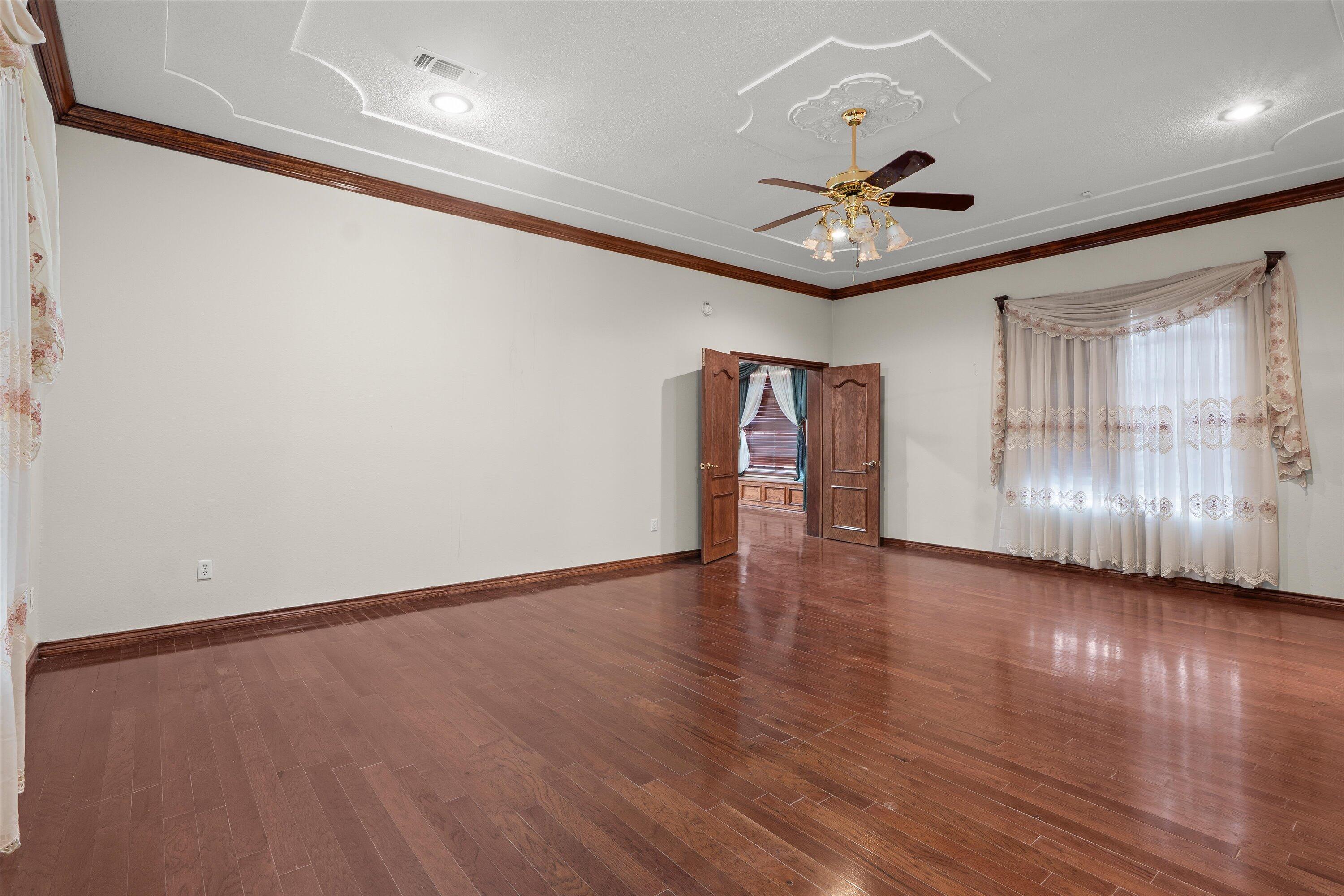 2404 York Avenue Lubbock, TX 79407 - Photo 23 of 88 an empty room with wooden floor chandelier fan and windows