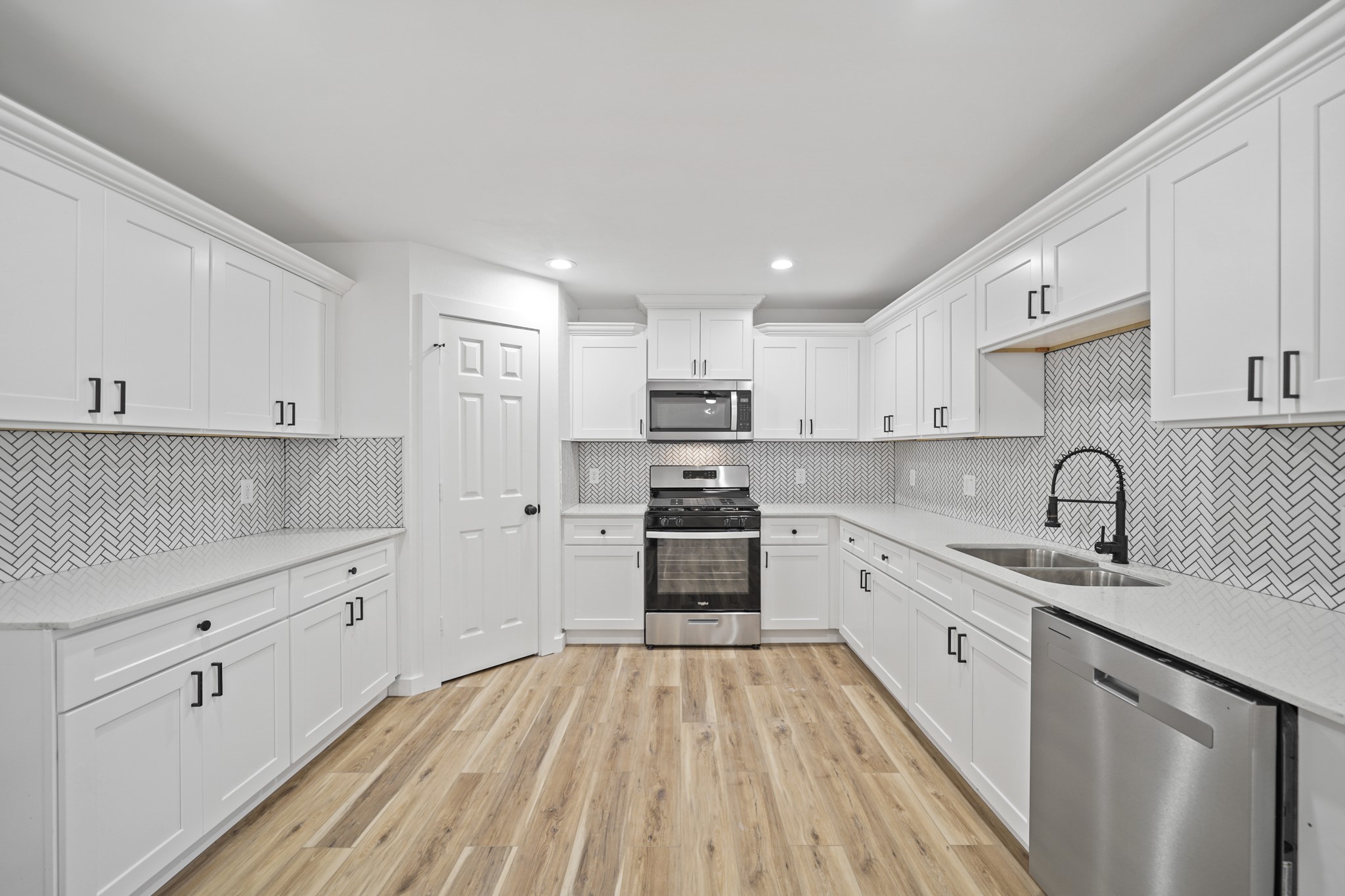 4154 Erby Street Houston, TX 77087 - Photo 25 of 36 a kitchen with stainless steel appliances granite countertop a sink dishwasher a refrigerator and white cabinets with wooden floor