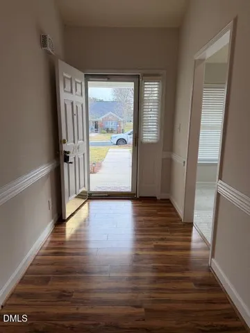 a view of an empty room with wooden floor fireplace and a window