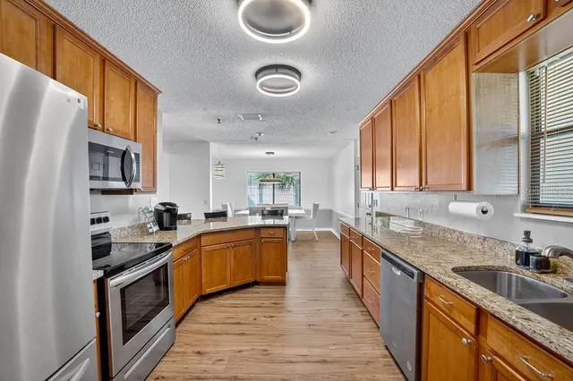 a kitchen with stainless steel appliances granite countertop a sink stove and refrigerator