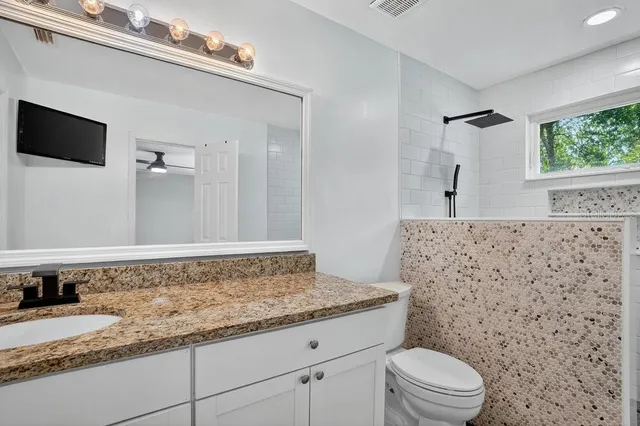 a bathroom with a granite countertop sink toilet and shower