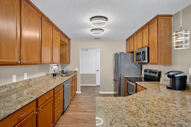 a kitchen with stainless steel appliances granite countertop a sink refrigerator stove and microwave