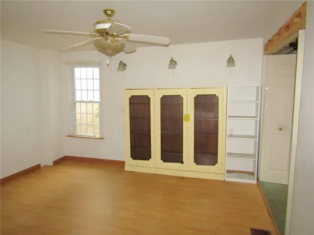 an empty room with windows and fan