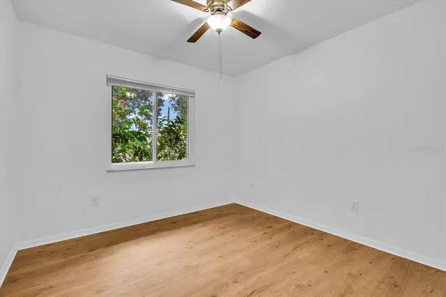 an empty room with a window and a ceiling fan