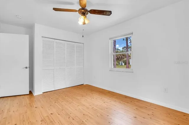 an empty room with a window and a ceiling fan