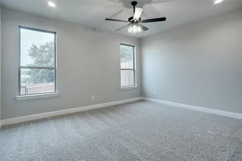 an empty room with windows and fan