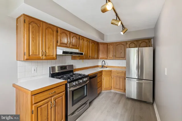 a kitchen with stainless steel appliances granite countertop a refrigerator a sink dishwasher a stove and a microwave oven on granite countertops