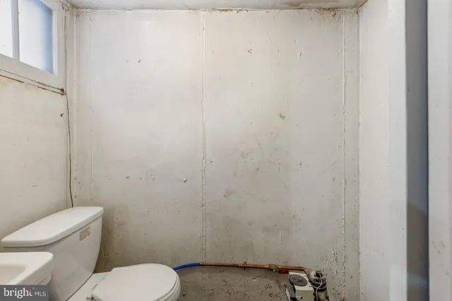 a white toilet sitting next to a white wall
