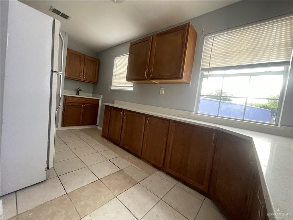 412 East 18th Street, Unit A Weslaco, TX 78596 - Photo 9 of 13 Kitchen with freestanding refrigerator, light tile patterned floors, and brown cabinets
