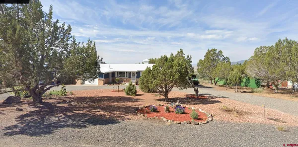 a backyard of a house with table and chairs under an umbrella