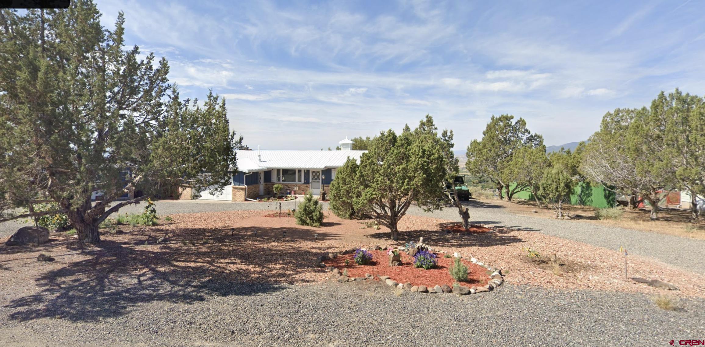 24207 Valley View Circle Cedaredge, CO 81413 - Photo 1 of 1 a backyard of a house with table and chairs under an umbrella