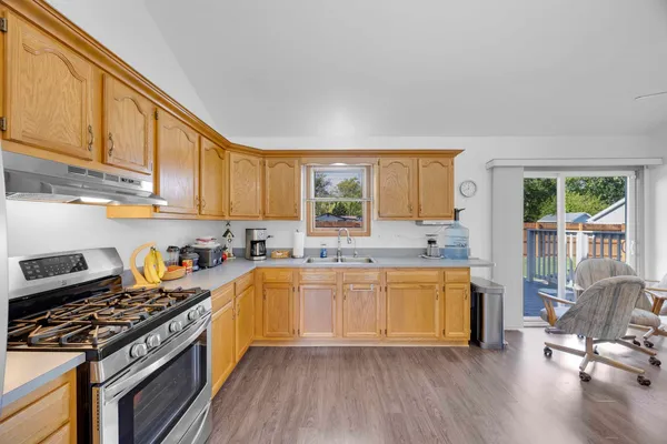 a kitchen with a stove a sink and wooden floor