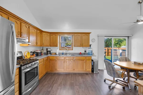 a kitchen with stainless steel appliances granite countertop a stove top oven a sink dishwasher a dining table and chairs with wooden floor