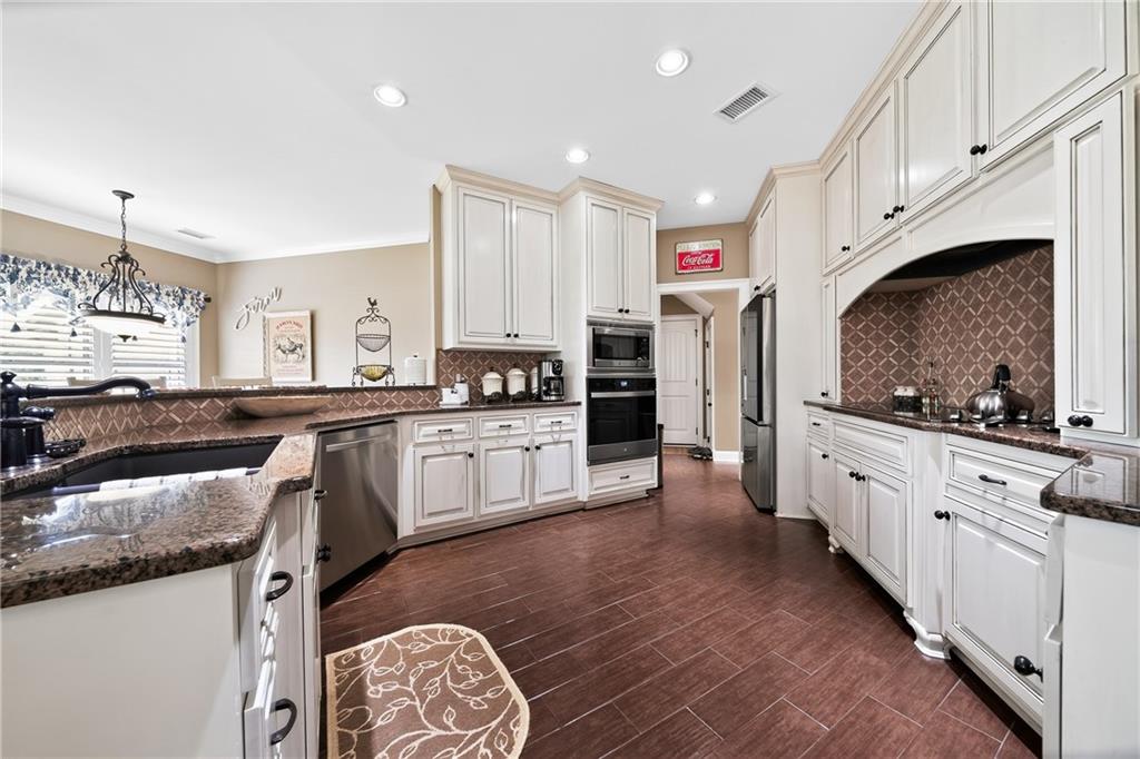 611 Padgetts Road Opelika, AL 36804 - Photo 15 of 64 Kitchen featuring white cabinetry, dark stone countertops, patterned tile backsplash, stainless steel appliances, and wood-finish flooring