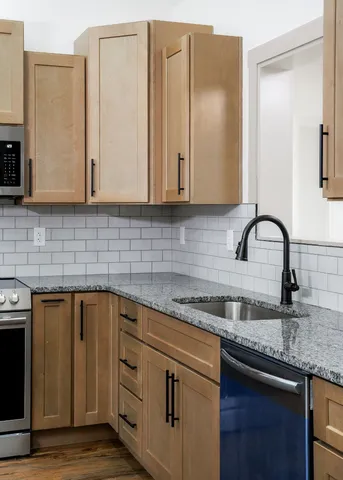 a kitchen with granite countertop a sink stainless steel appliances and cabinets