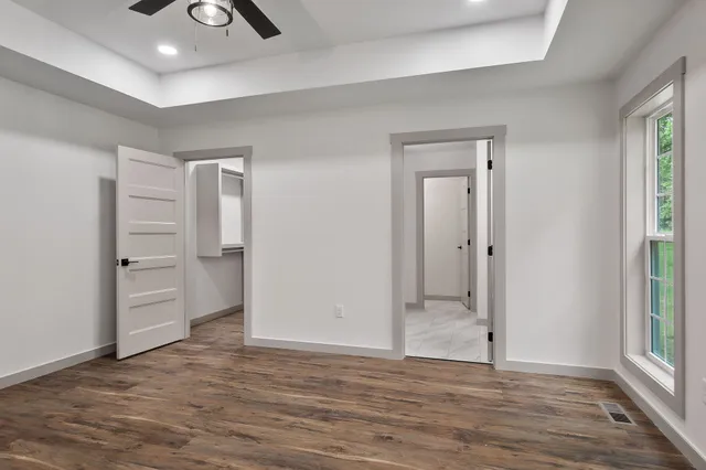 an empty room with wooden floor cabinet and windows