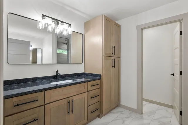 a bathroom with a granite countertop sink and a mirror