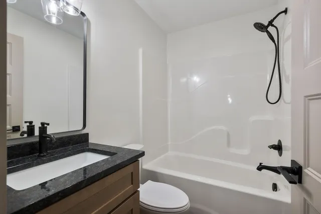 a bathroom with a granite countertop sink toilet and shower