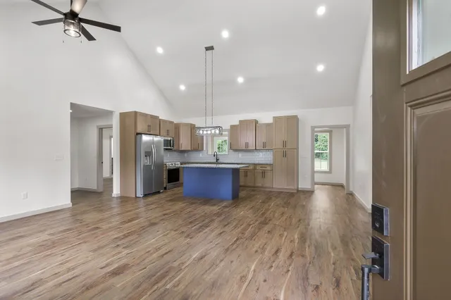 a view of kitchen with stainless steel appliances refrigerator wooden floor and window