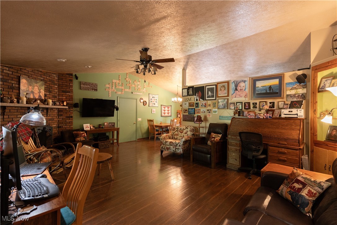 7946 Kennard Road Lodi, OH 44254 - Photo 10 of 20 Living room with dark wood-type flooring, ceiling fan, vaulted ceiling, and a textured ceiling