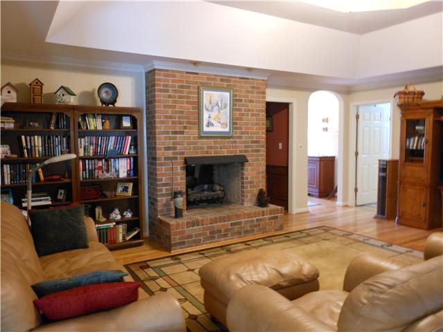 489 Pond Apple Road Clarksville, TN 37043 - Photo 6 of 17 The Great Room features a tray ceiling, ceiling fan, hardwood flooring, and see-thru brick fireplace with remote control gas logs.