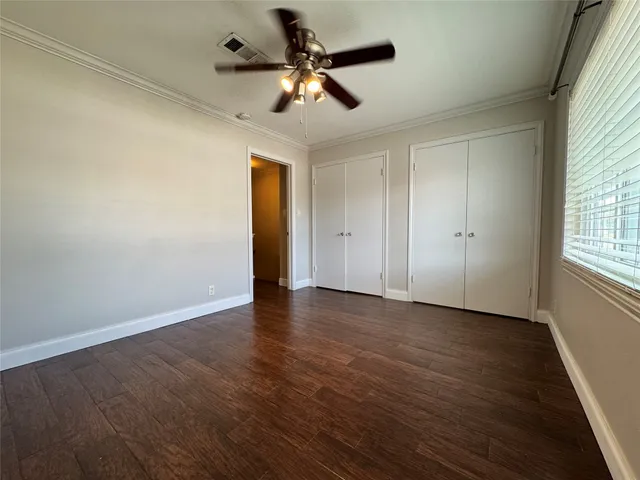 an empty room with wooden floor chandelier fan and windows