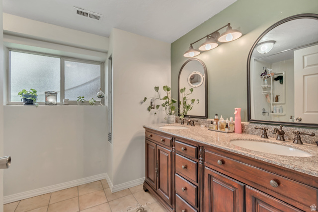 7470 Ramanee Drive Midvale, UT 84047 - Photo 21 of 29 Full bathroom with double vanity, light tile patterned floors, and a tub and shower