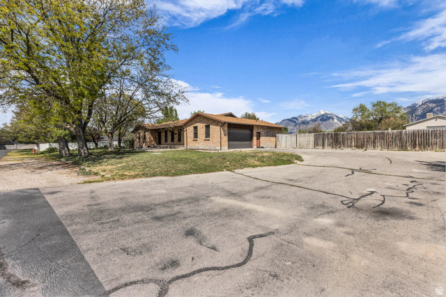 10705 Green Ridge Drive Sandy, UT 84070 - Photo 5 of 55 View of front of property with concrete driveway, brick siding, a mountain view, and an attached garage