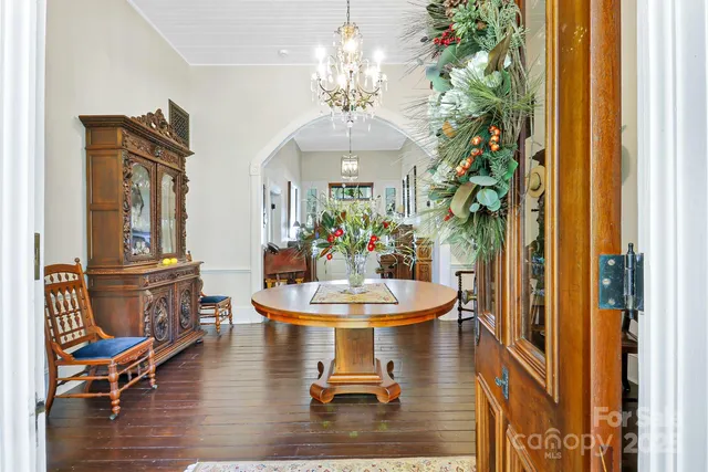 a dining room with chandelier and wooden floor