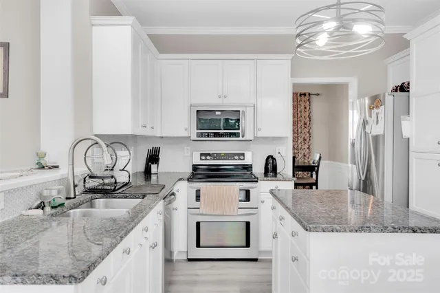 a kitchen with granite countertop a sink and a stove top oven with wooden floor