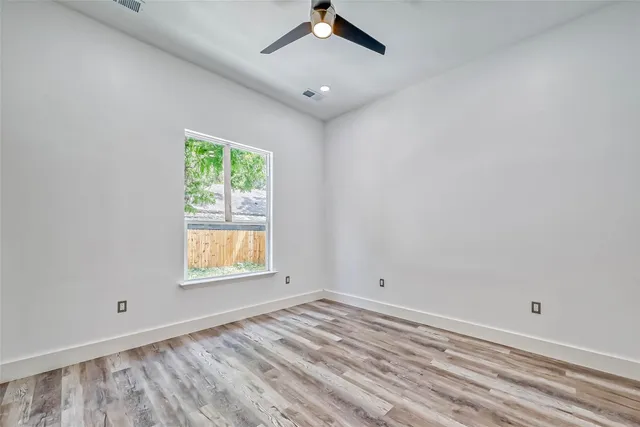 an empty room with a window and a ceiling fan