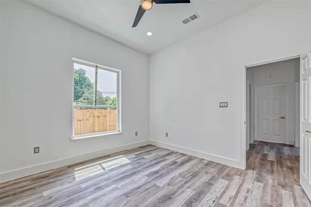 an empty room with wooden floor cabinet and windows