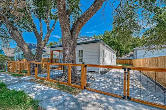 a view of a house with wooden fence next to a large tree