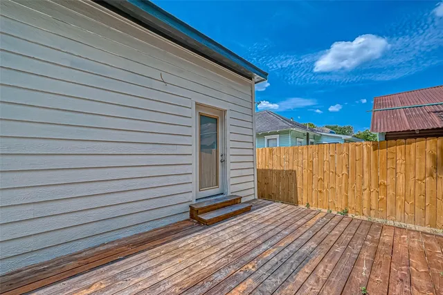 a backyard of a house with wooden fence and a tree