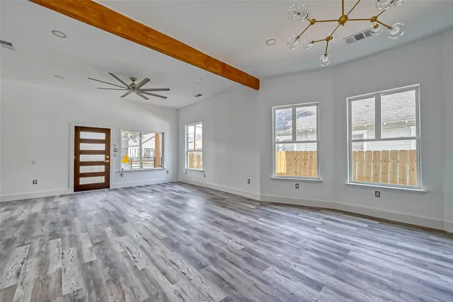a view of an empty room with a window and wooden floor
