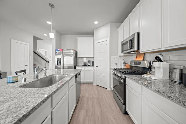 a kitchen with granite countertop a sink stove and cabinets