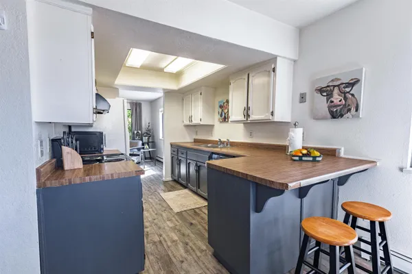 a kitchen with kitchen island granite countertop a table chairs a stove a sink and a refrigerator