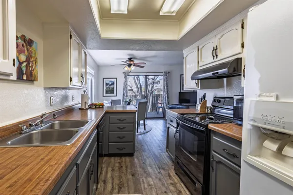 a kitchen with granite countertop a sink wooden cabinets and stainless steel appliances