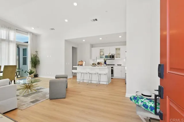 a living room with furniture a wooden floor and a kitchen