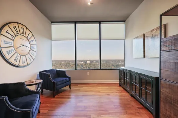 a living room with furniture a large window and wooden floor