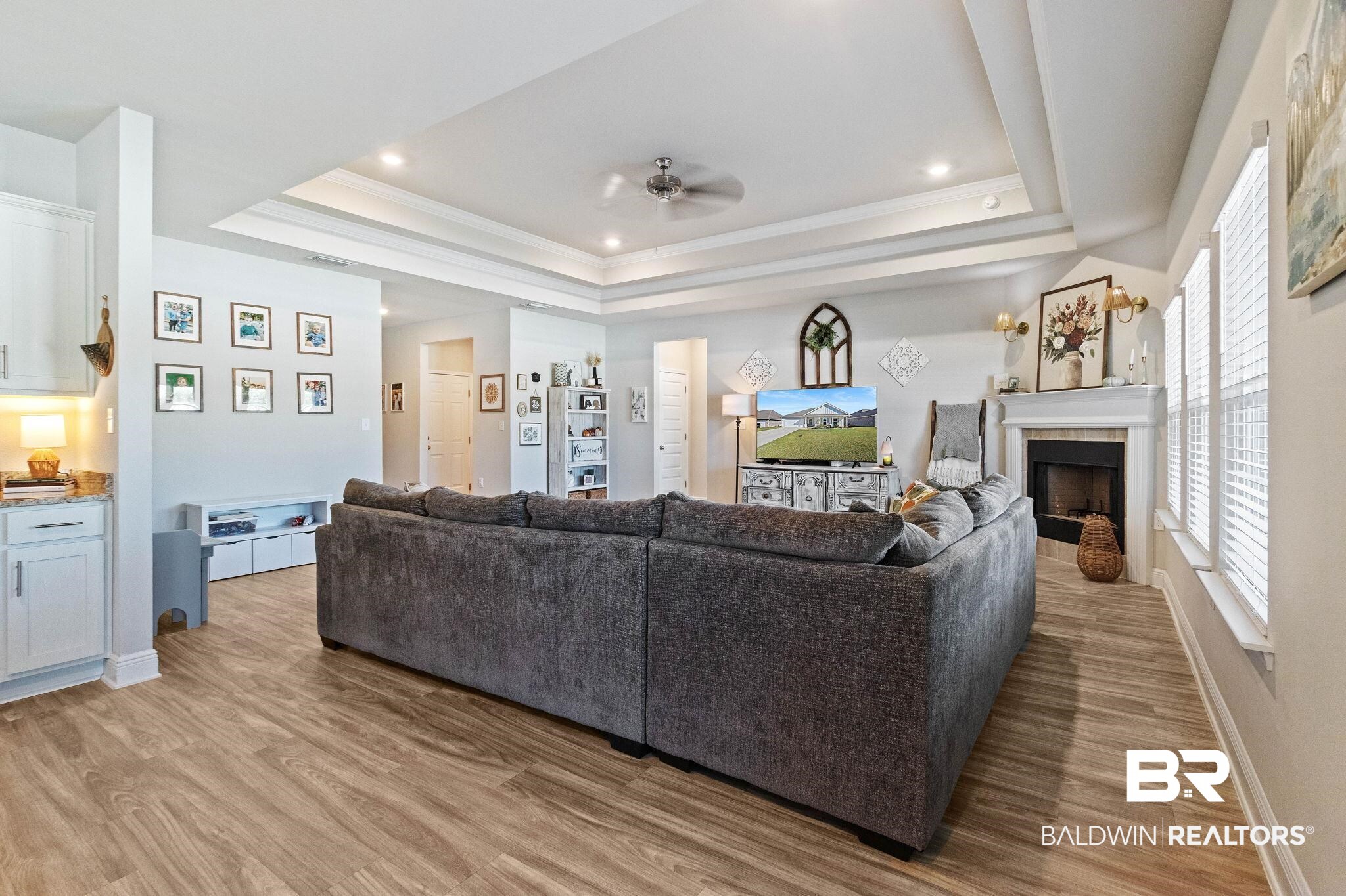 24939 Spectacular Bid Loop Daphne, AL 36526 - Photo 8 of 38 Living area with a tray ceiling, ornamental molding, a fireplace, light wood-style floors, and ceiling fan