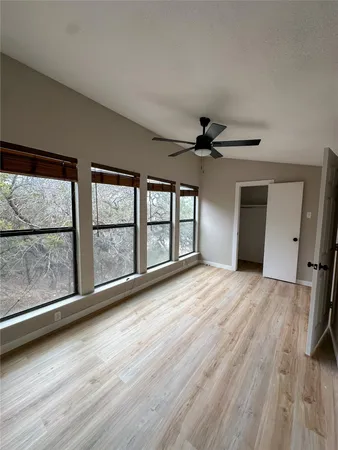 a view of an empty room with a window and wooden floor