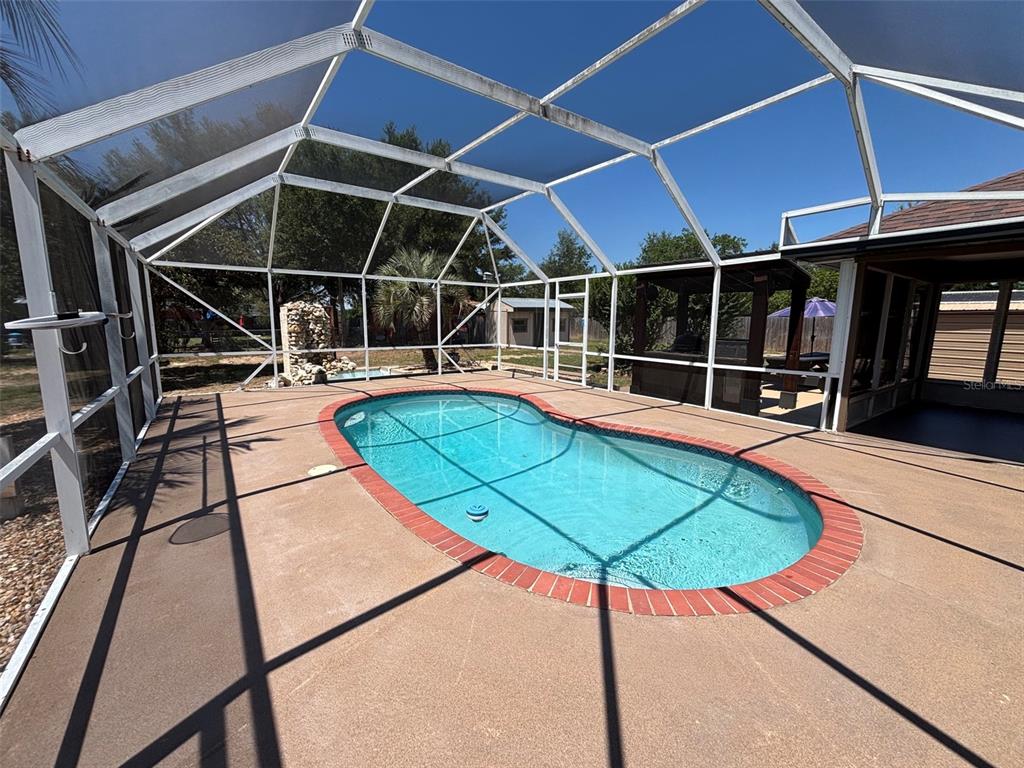 9801 Southeast Sunset Harbor Road Summerfield, FL 34491 - Photo 28 of 37 a view of a swimming pool with a chair and table