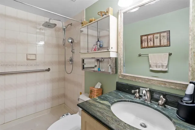 a bathroom with a granite countertop sink a mirror and a shower